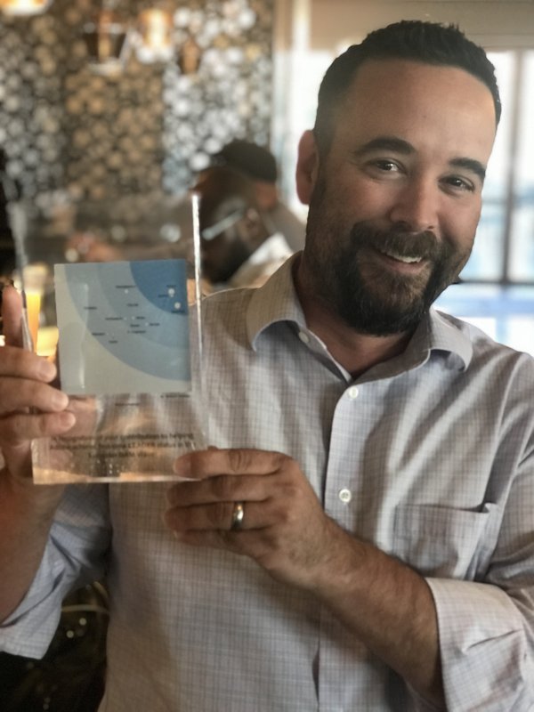 Joshua Ramirez holding the Forrester Wave Leader award for Adobe Experience Manager Assets, 2018